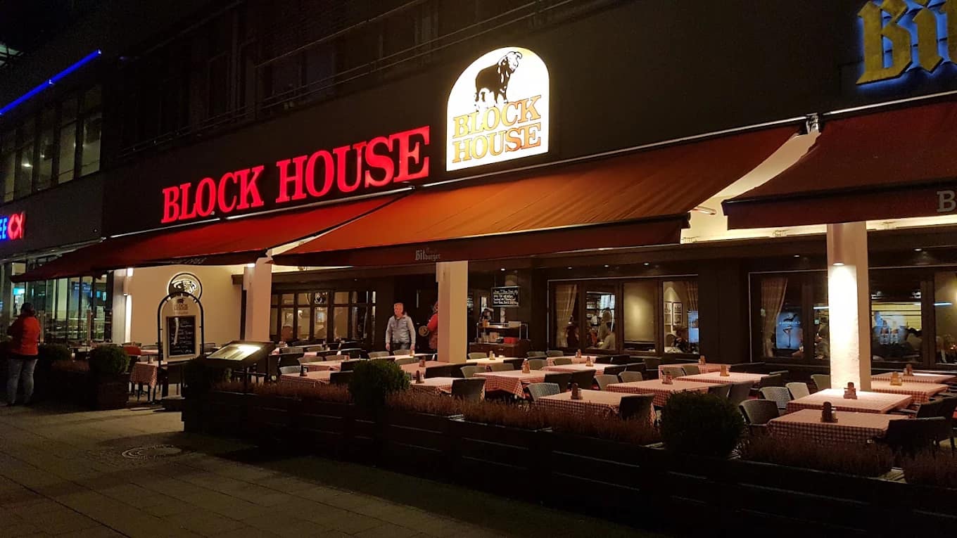 BLOCK HOUSE Restaurant mit beleuchteter Außenfassade und Terrasse am Abend